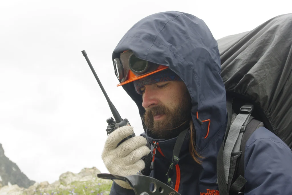 薄手のグローブを着けたまま無線機を操作する登山者