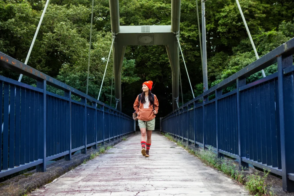 ニット帽をかぶって、山の吊り橋を渡るハイカー