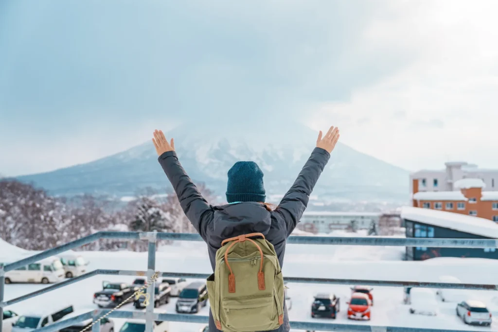 ニット帽とザック姿で、雪の羊蹄山を望む人