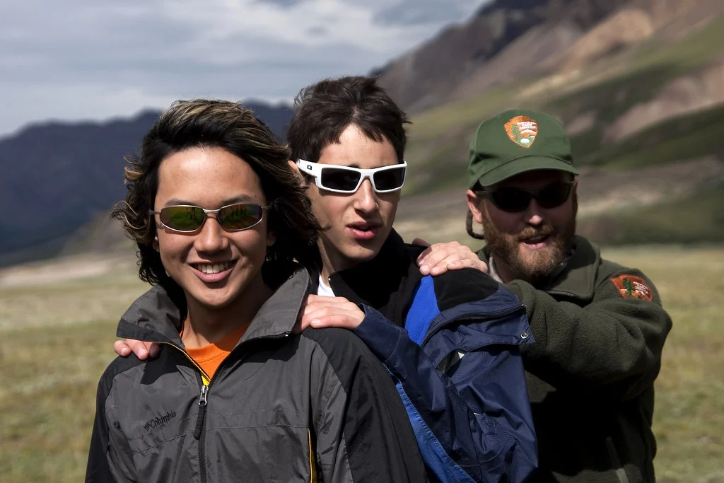 山の草地で、サングラスをかけた登山者たち