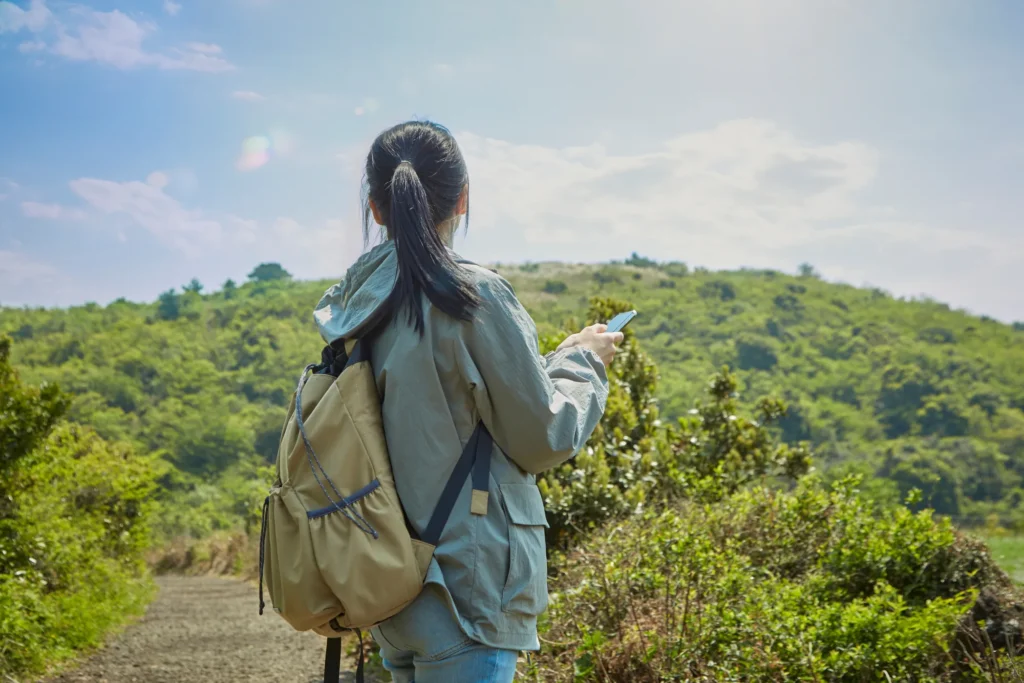 丘の上で景色を眺める登山者の後ろ姿