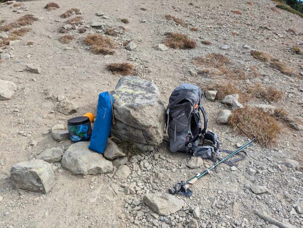 登山道の岩の脇に置いた、丸めたマットとザック