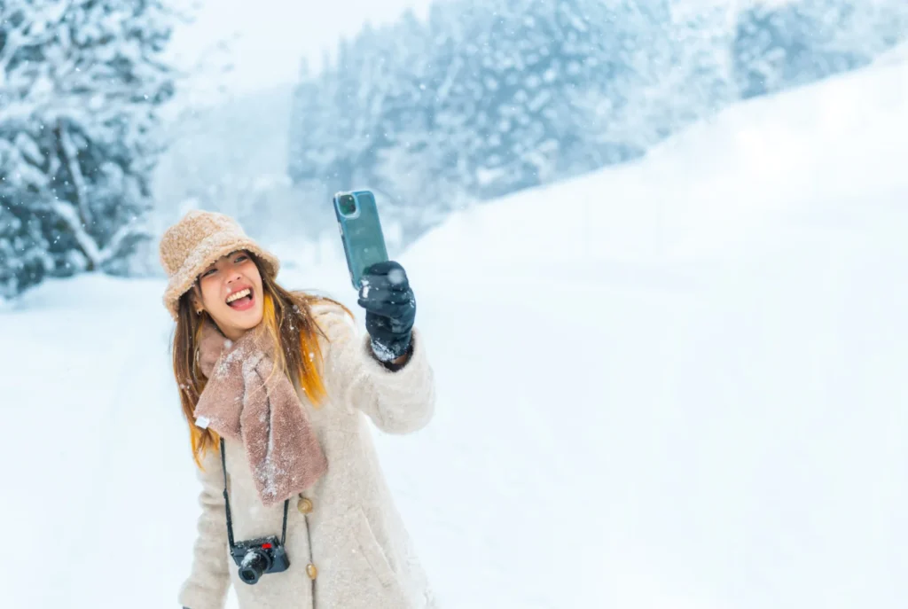 ニット帽とマフラーで雪の森を歩く女性